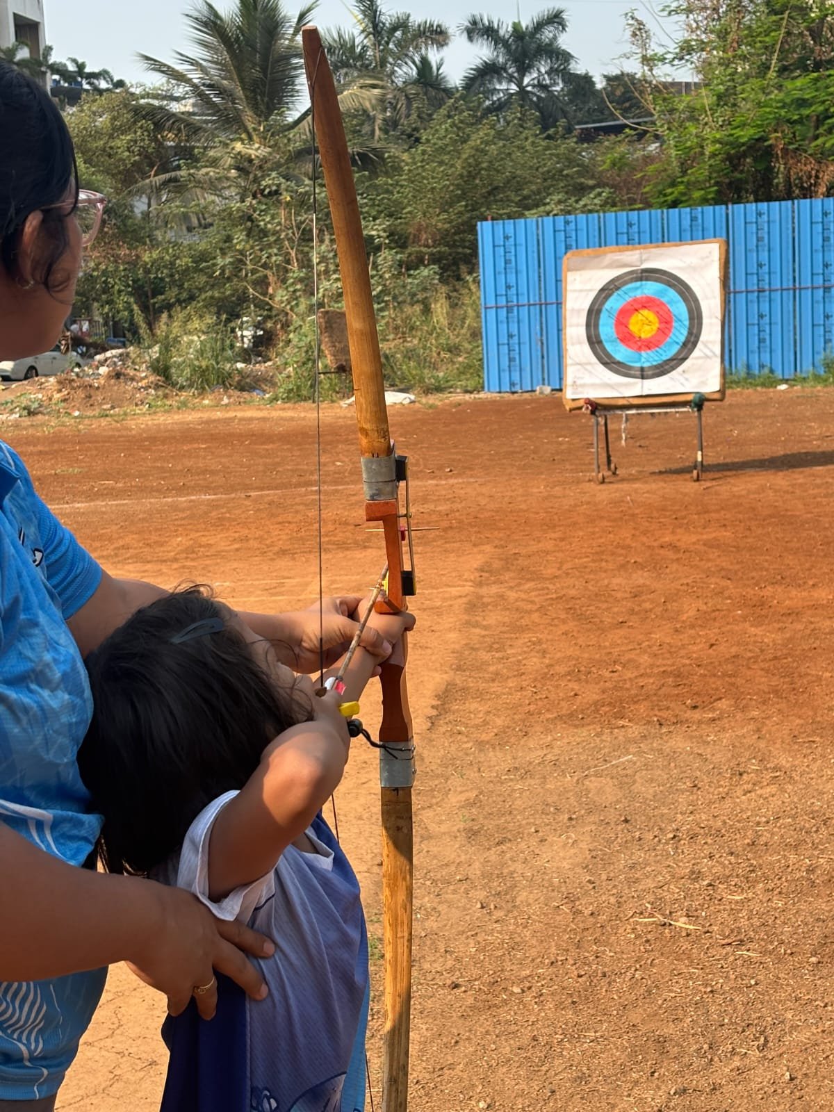 A young archer practicing with guidance from an instructor